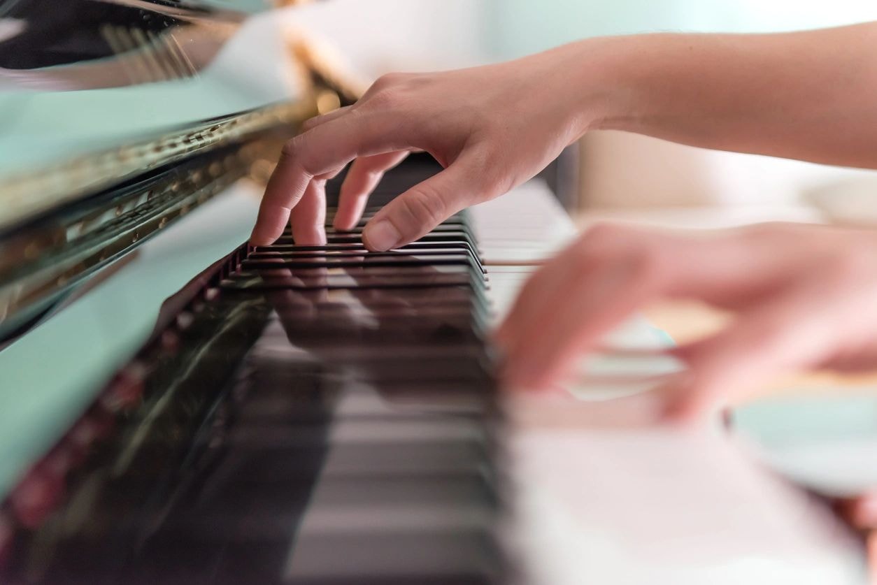 Hands playing piano keyboard