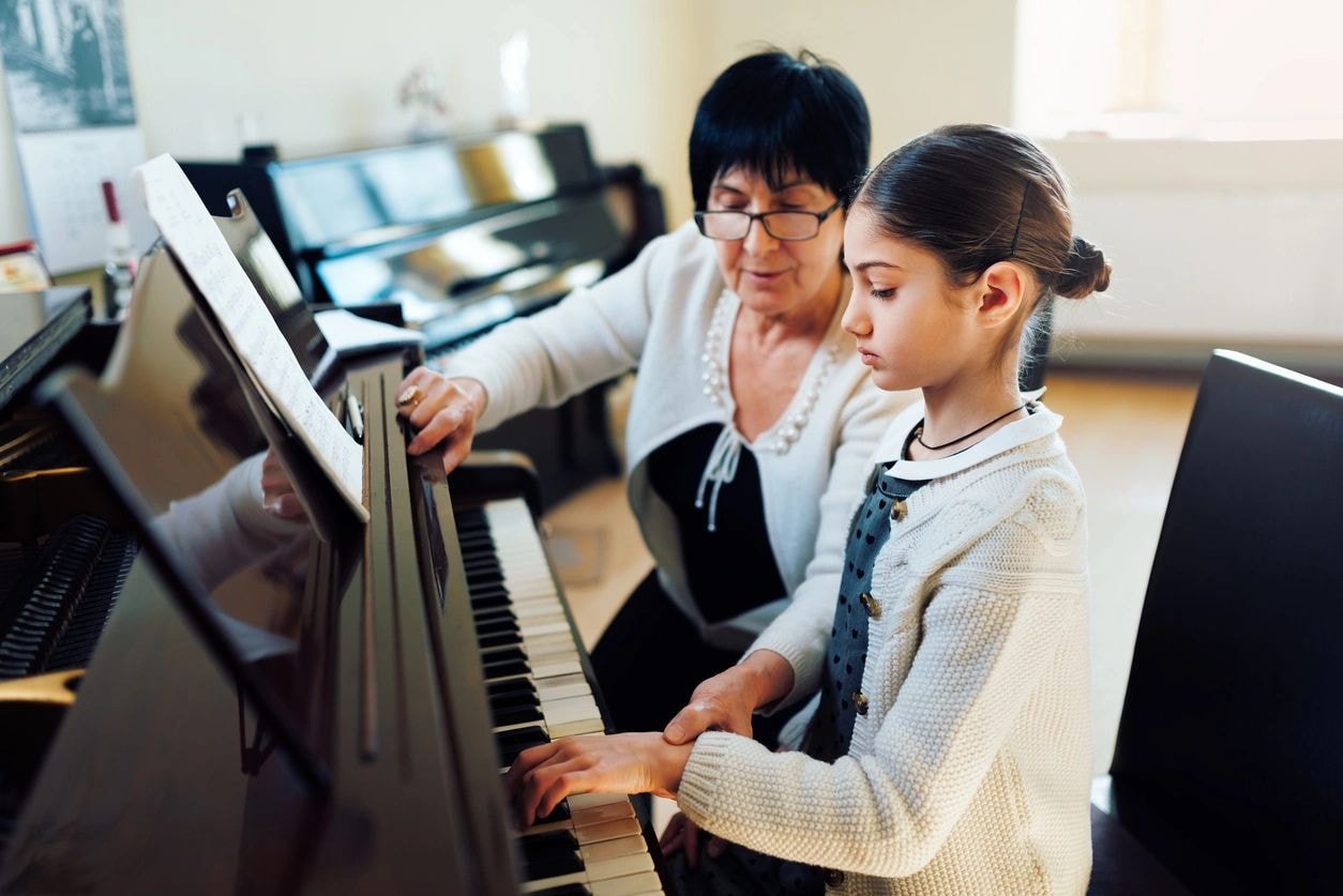 Piano teacher instructing a young student
